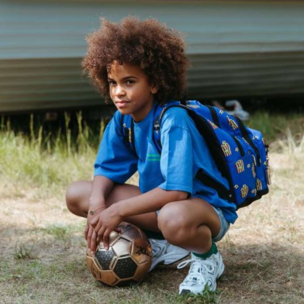 Kinderrugzak in felblauw met popcorn- en voetbalprint van Little Legends, geschikt voor kinderen van 5 t/m 12 jaar op model