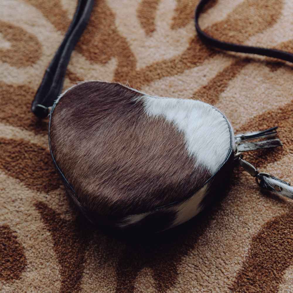 leren hartvormige tas met koeienprint op de vloer