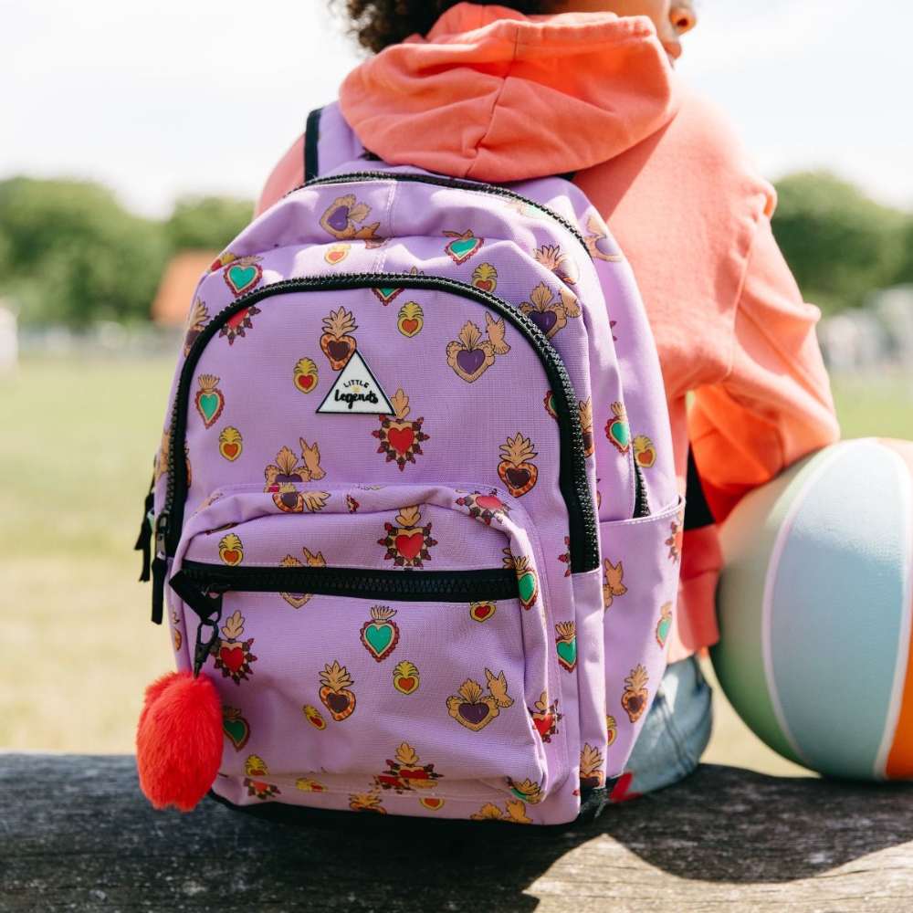 Lila kinderrugzak met kleurrijke hartjes geïnspireerd op Mexicaanse Milagros-symbolen en fluffy hartvormige sleutelhanger op model