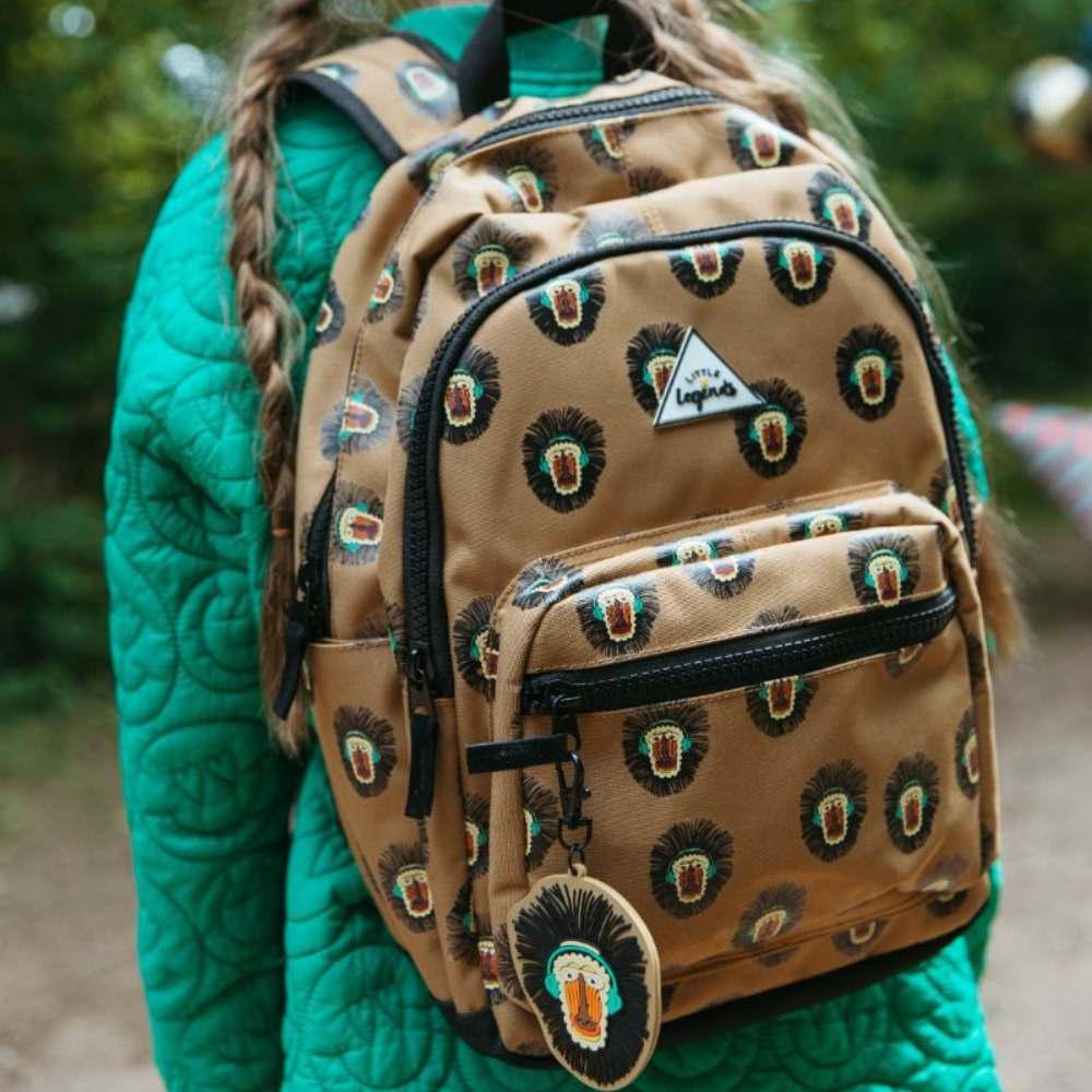 Camelkleurige kinderrugzak met baboon print, knaloranje snoet, koptelefoon en grove zwarte ritsen op model